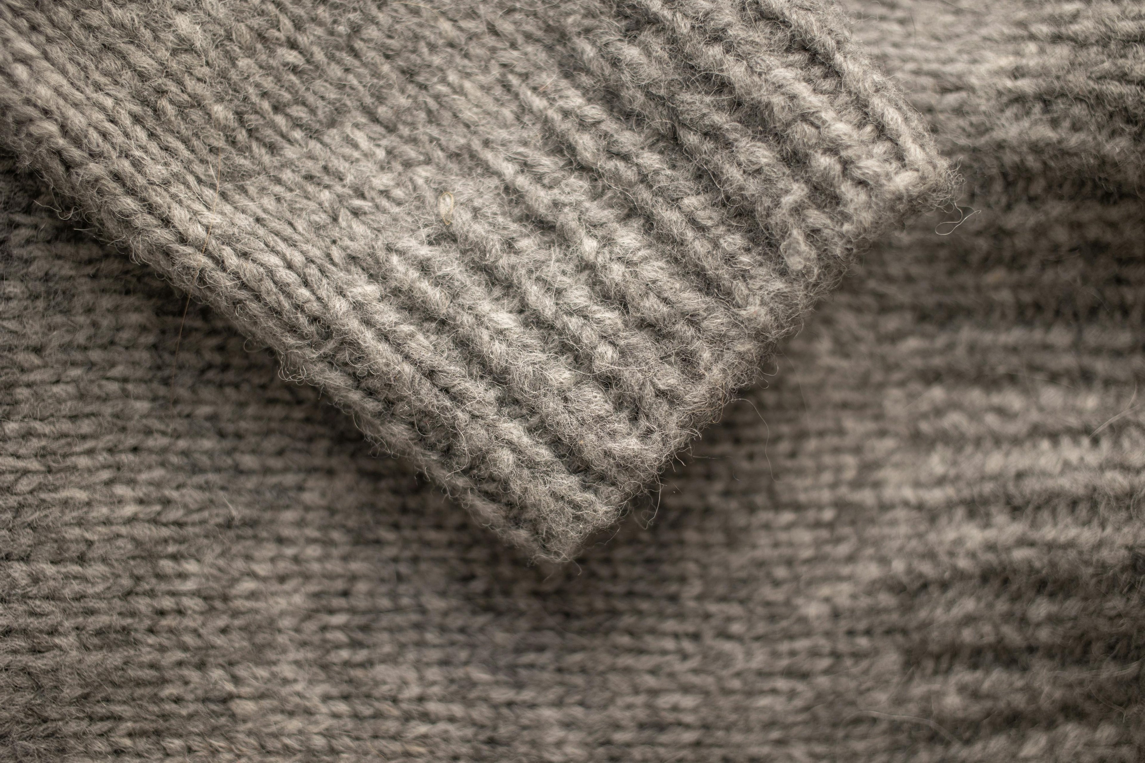 Close-up of a gray knitted sweater with a focus on texture and pattern.